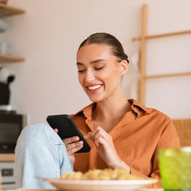 Woman smiling while looking at phone at home