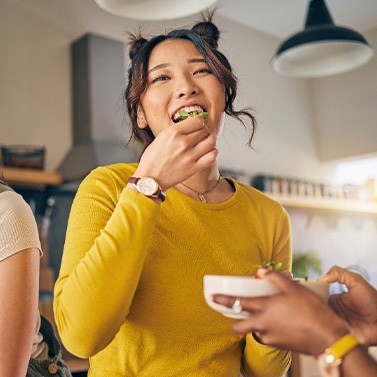 Group of friends smiling while eating meal in kitchen