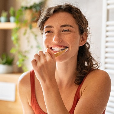 Patient smiling while brushing her teeth
