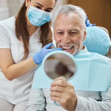A man looking in the mirror at his newly improved smile