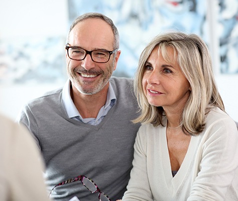 Man and woman smiling while talking to their dentist