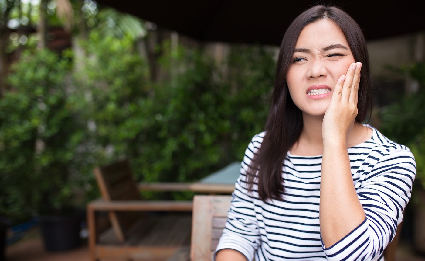 Woman in need of emergency dentistry holding cheek in pain