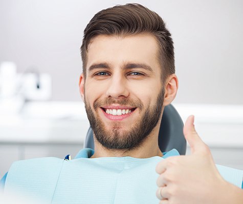 Man in dental chair smiling and giving thumbs up