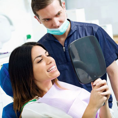 Dental patient looking at her smile in mirror