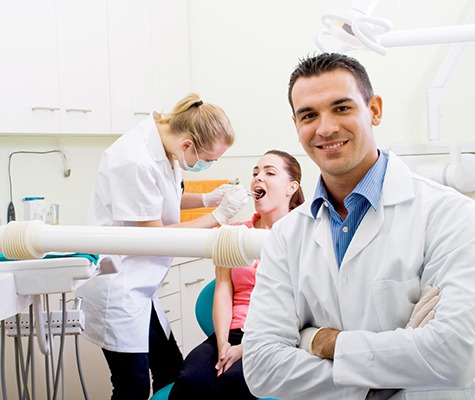 Dentist smiling and folding his arms in front of patient.
