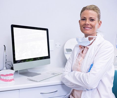 Associate dentist in Dallas smiling and folding arms.