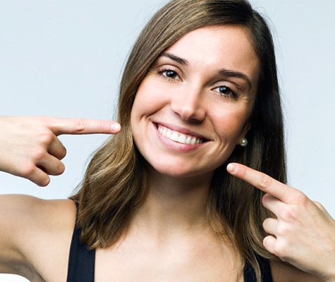 Woman pointing to her teeth after BioClear in Lancaster.