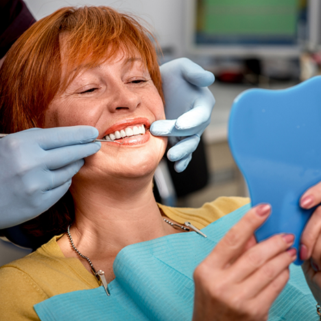 Senior woman checking smile in handheld mirror