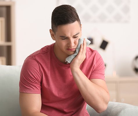 Man in need of emergency dentistry holding jaw in pain