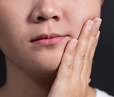 Closeup of person with toothache holding cheek