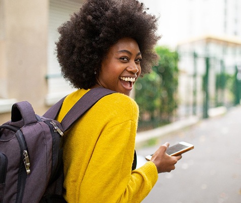 a smiling person with their phone in their hand