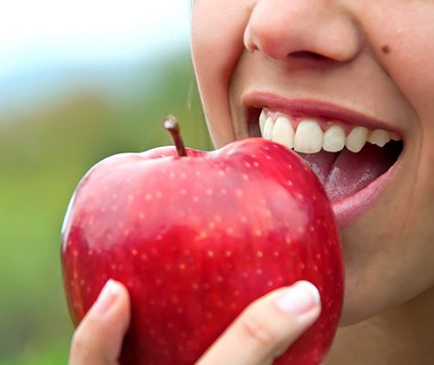 Closeup of patient with dental implant dentures in Lancaster eating an apple