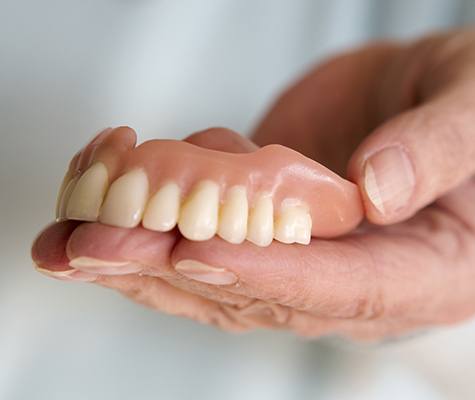 Hand holding full denture