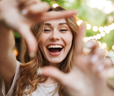 Woman framing smile with fingers