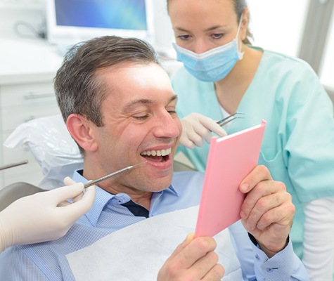 Man looking at his smile after teeth in a day tooth replacement