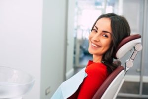 Woman wearing a red sweater sitting in the dental chair smiling