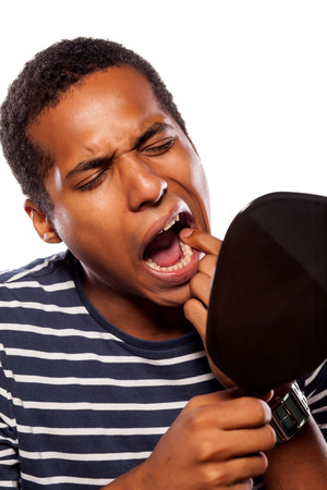 Man with loose tooth looking in a hand mirror