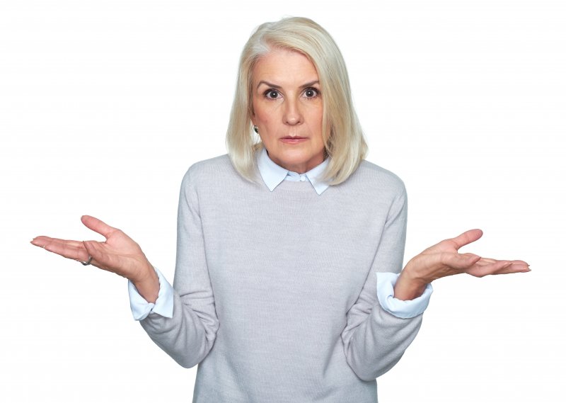 An older woman shrugging, wondering why her lower denture is so loose
