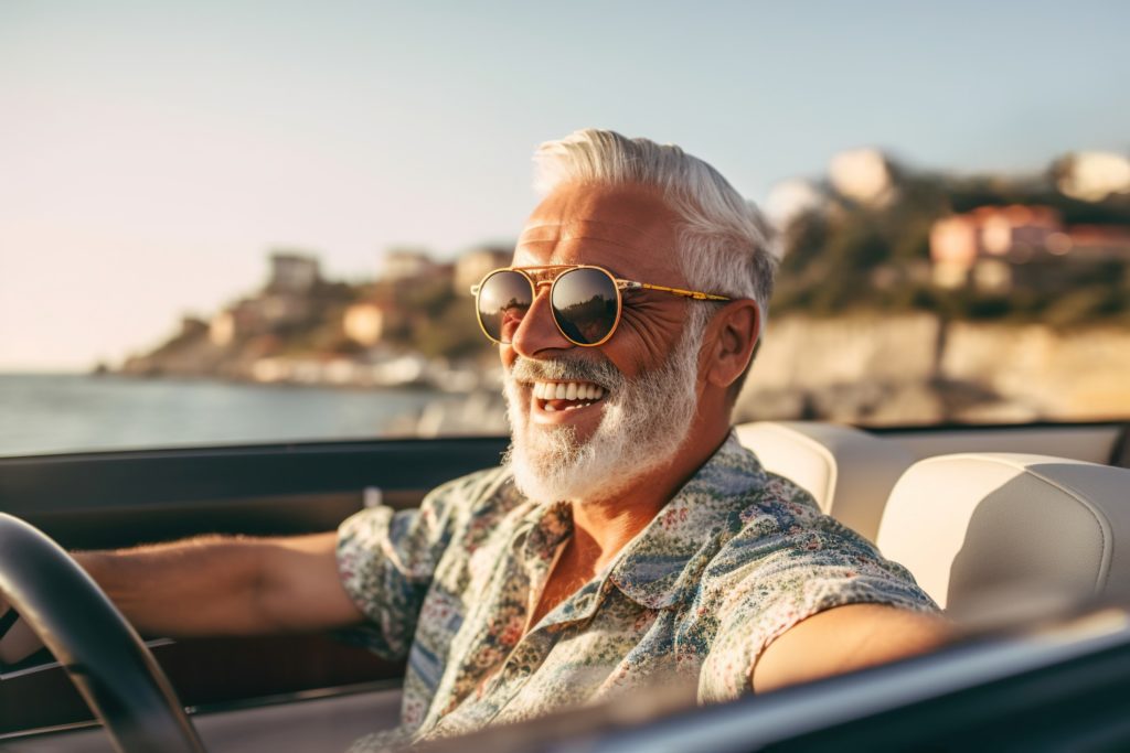 Man smiling while driving convertible along beach