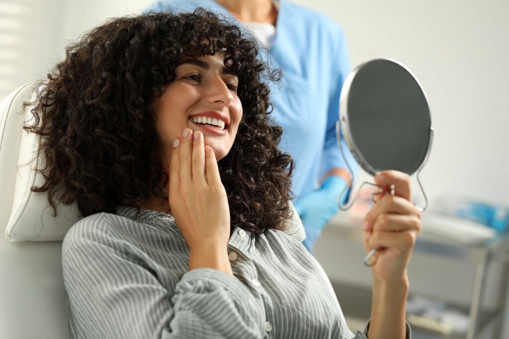 A woman smiling in a mirror at a dentist’s office.