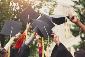 Students holding up graduation hats. 
